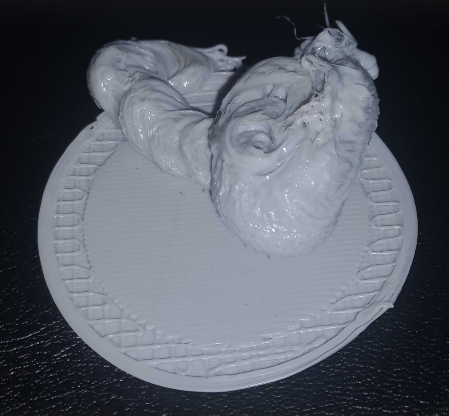 Невдала спроба 3D-друку: клубок світло-сірого пластику, що налип на основу, утворивши химерну грудку замість готової деталі.