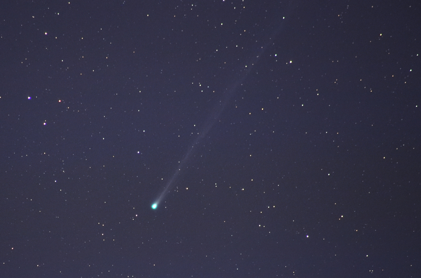 Комета C/2025 R3 (PanSTARRS) на тлі темного зоряного неба; її яскрава бірюзова голова розташована трохи нижче центру, а довгий світлий хвіст простягається по діагоналі вгору.